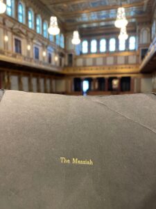 Im Vordergrund eine Notenausgabe von Händels "The Messiah", im Hintergrund der Goldene Saal des Wiener Musikvereins